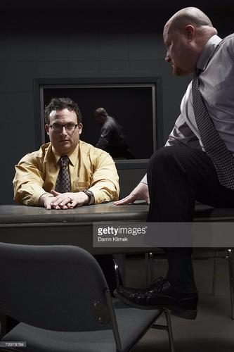 напряженная сцена допроса в темной комнате, двое мужчин