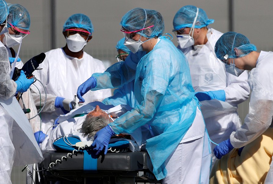 French rescue team wearing protective suits carry a patient on a ...