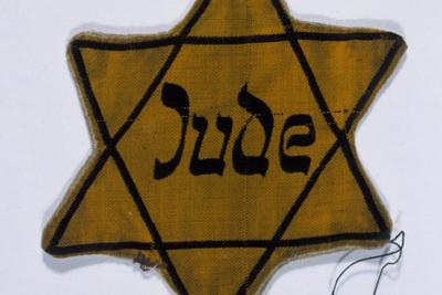 A yellow star of David marked with the German word for Jew (Jude) worn ...