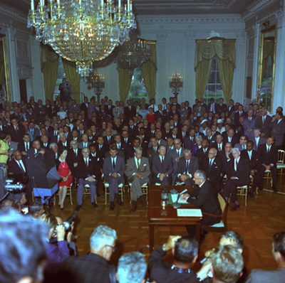 Lyndon B. Johnson signs the Civil Rights Act.